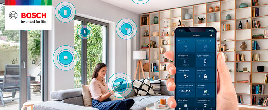 Bosch Smart Home App zeigt Favoriten wie Alarm, Türen, Raumtemperatur und Rauchmelder im Smart Home mit Frau auf Sofa