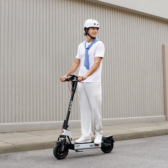 Junges Paar trägt zusammenklappbare Navee G E-Scooter die Treppe hinunter – kompakt und einfach zu transportieren