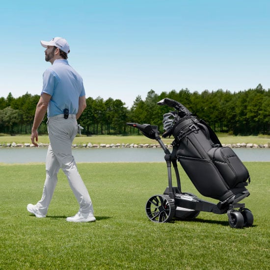 Golfer läuft neben dem Navee Elektro-Golftrolley mit Golfbag auf dem Golfplatz