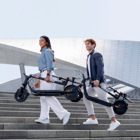 Junges Paar trägt zusammenklappbare Navee V E-Scooter die Treppe hinunter – kompakt und einfach zu transportieren