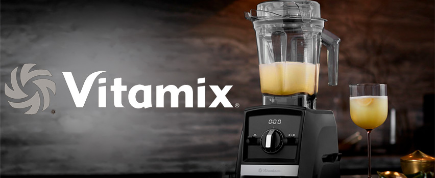 Vitamix Blender mit gelbem Smoothie im Behälter und im Glas neben Logo mit Slogan Neue Abenteuer warten